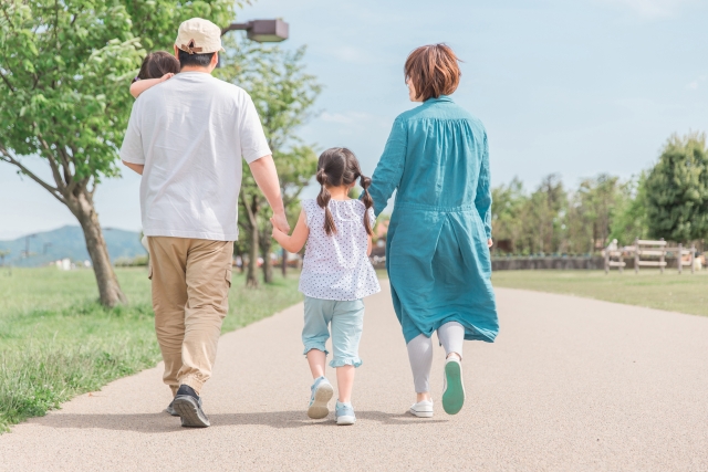 公園を歩く家族の後ろ姿